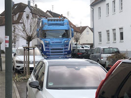 Scania LKW neben parkenden Autos